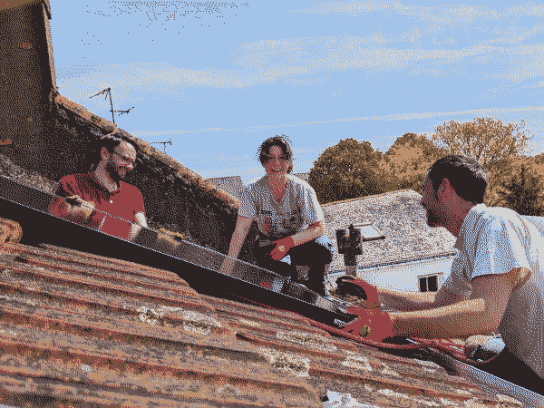 3 personnes installent des panneaux solaires sur une toiture tuile